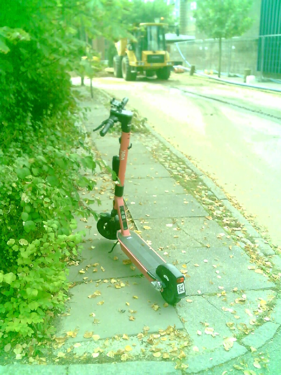 A scooter parked in the middle of the pavement.