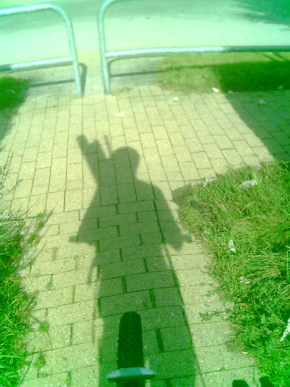 The shadow of a person on a bicycle, large objects protruding above the figure.